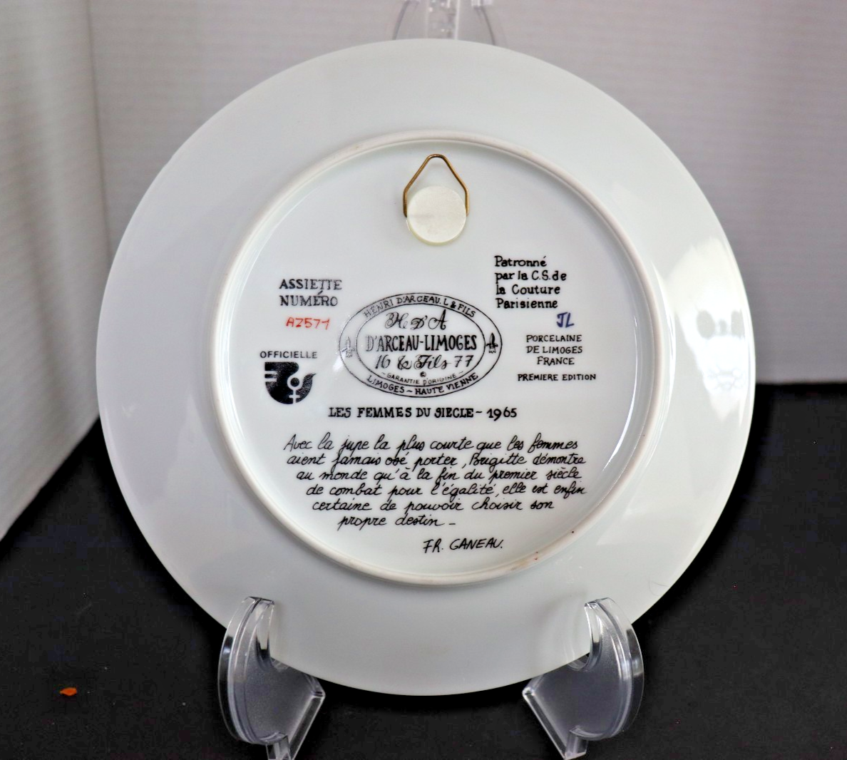 Decorative plate with text and branding on a stand against a neutral background