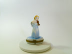 Decorative figurine of a woman playing a violin on a white base against a white background