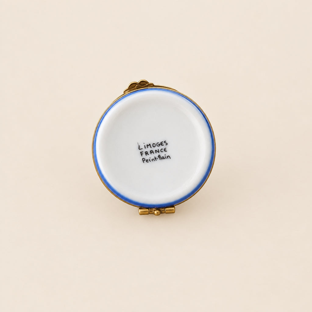 A vintage French enamel pin by Ladybird Laugh, featuring a white enamel face with a blue rim, photographed from the back on a white circular display stand against a neutral gray background.