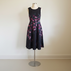 Black dress with pink floral pattern on a mannequin against a white background