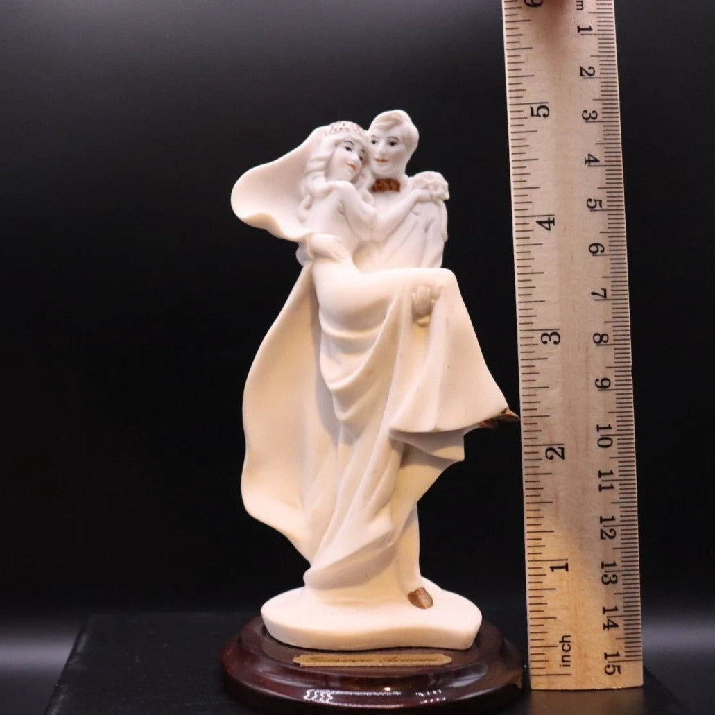 Statue of a couple embracing next to a ruler for scale on a black background