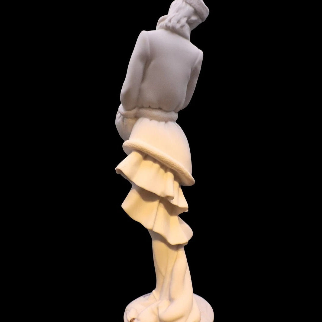 White marble statue of a figure with a flowing skirt on a black background