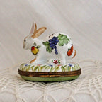 Decorative ceramic rabbit with fruit designs on a white lace background