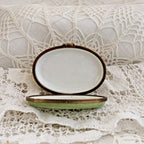 Small oval dish with gold rim on a white lace fabric