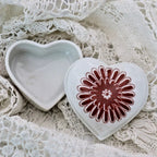 Heart-shaped ceramic box with a red floral design on a lace background