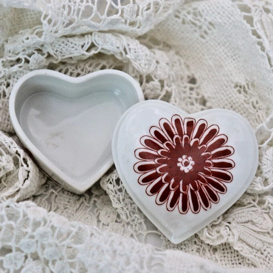 Heart-shaped ceramic box with a red floral design on a lace background