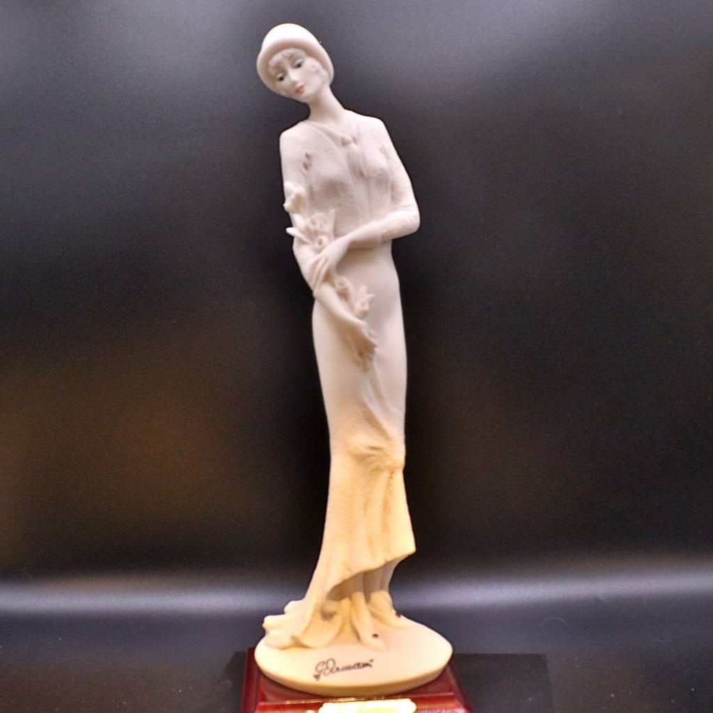White ceramic figurine of a woman on a dark background