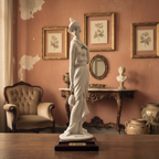 Statue in a room with decorative elements and framed pictures on the wall.