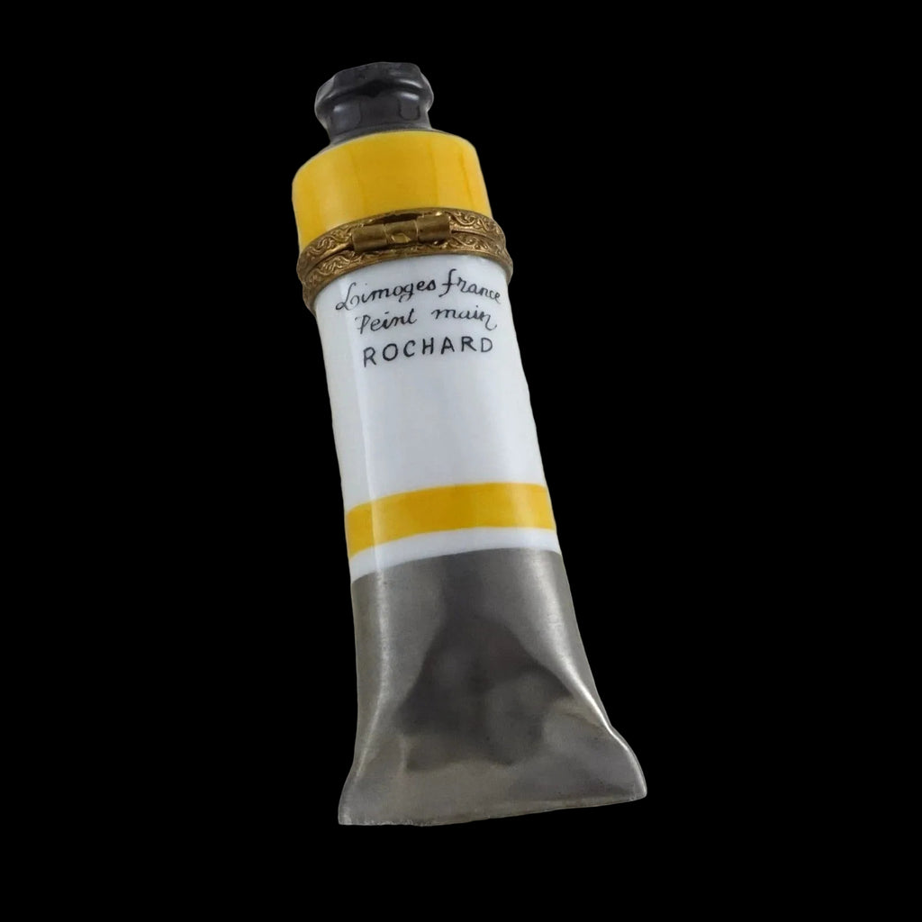 Paint tube with yellow and white design on a textured white background