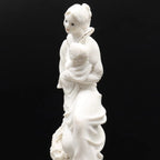 White ceramic figure of a woman holding a child on a black background