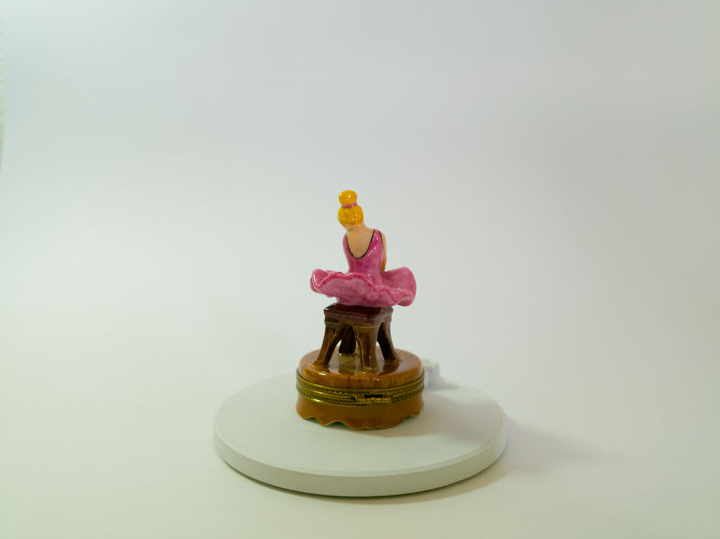 Small figurine of a person in a pink outfit on a white base with a white background