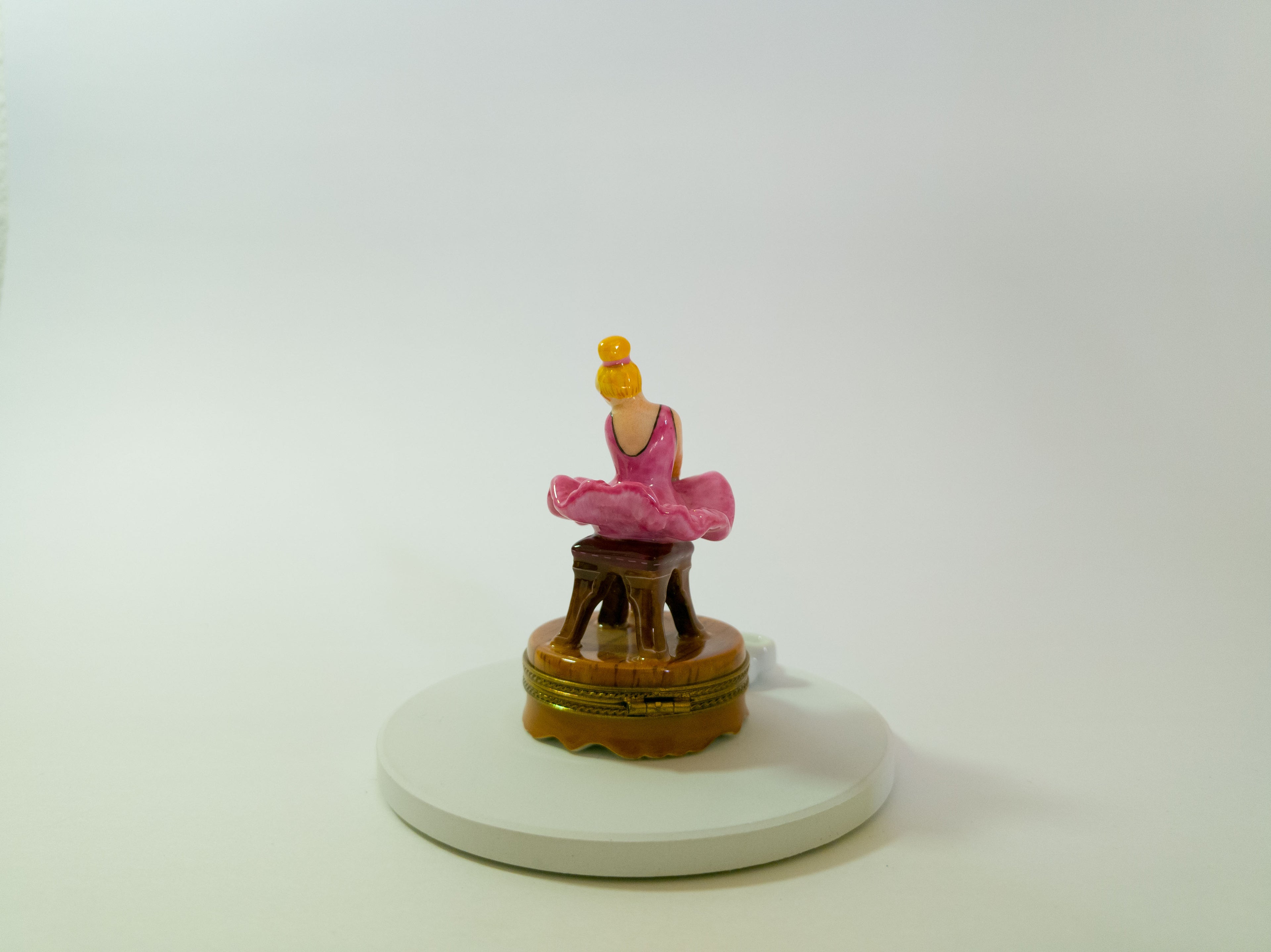 Small figurine of a person in a pink outfit on a white base with a white background