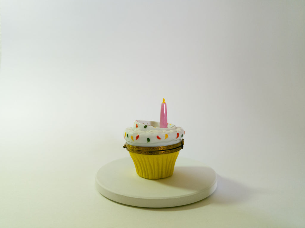 Cupcake-shaped container with a candle on a white background