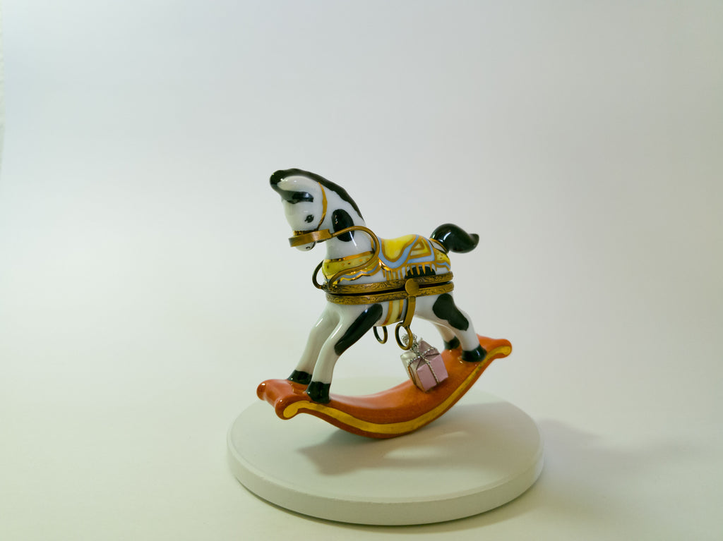 Small rocking horse figurine on a white base with a plain background