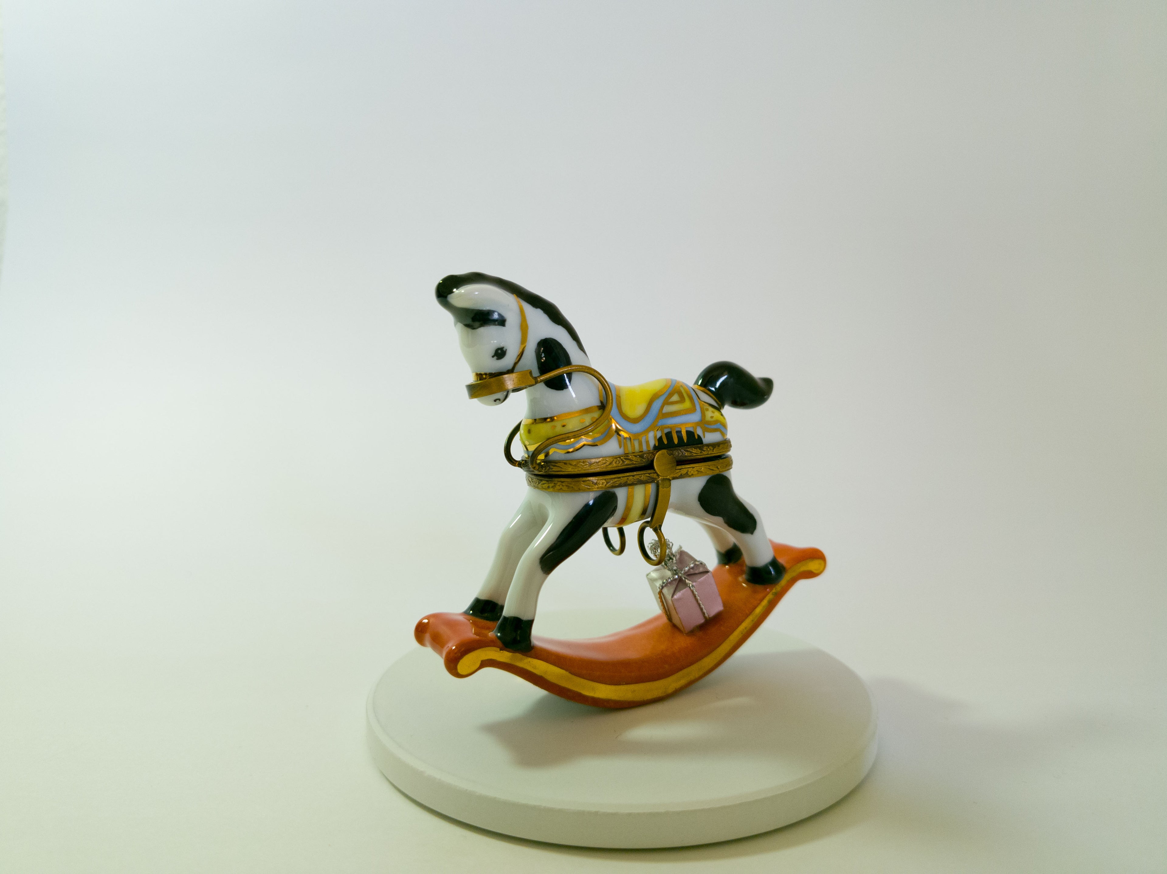 Small rocking horse figurine on a white base with a plain background