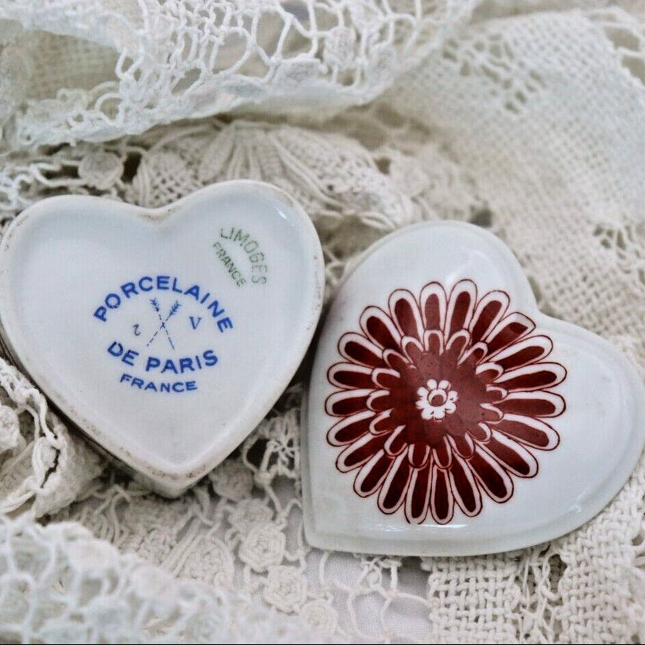 Top and bottom of heart-shaped porcelain trinket box on a lace background, one with 'Porcelaine de Paris France' text and the other with a floral design.