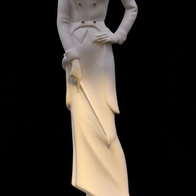 White ceramic figurine of a person holding a heart-shaped object on a black background