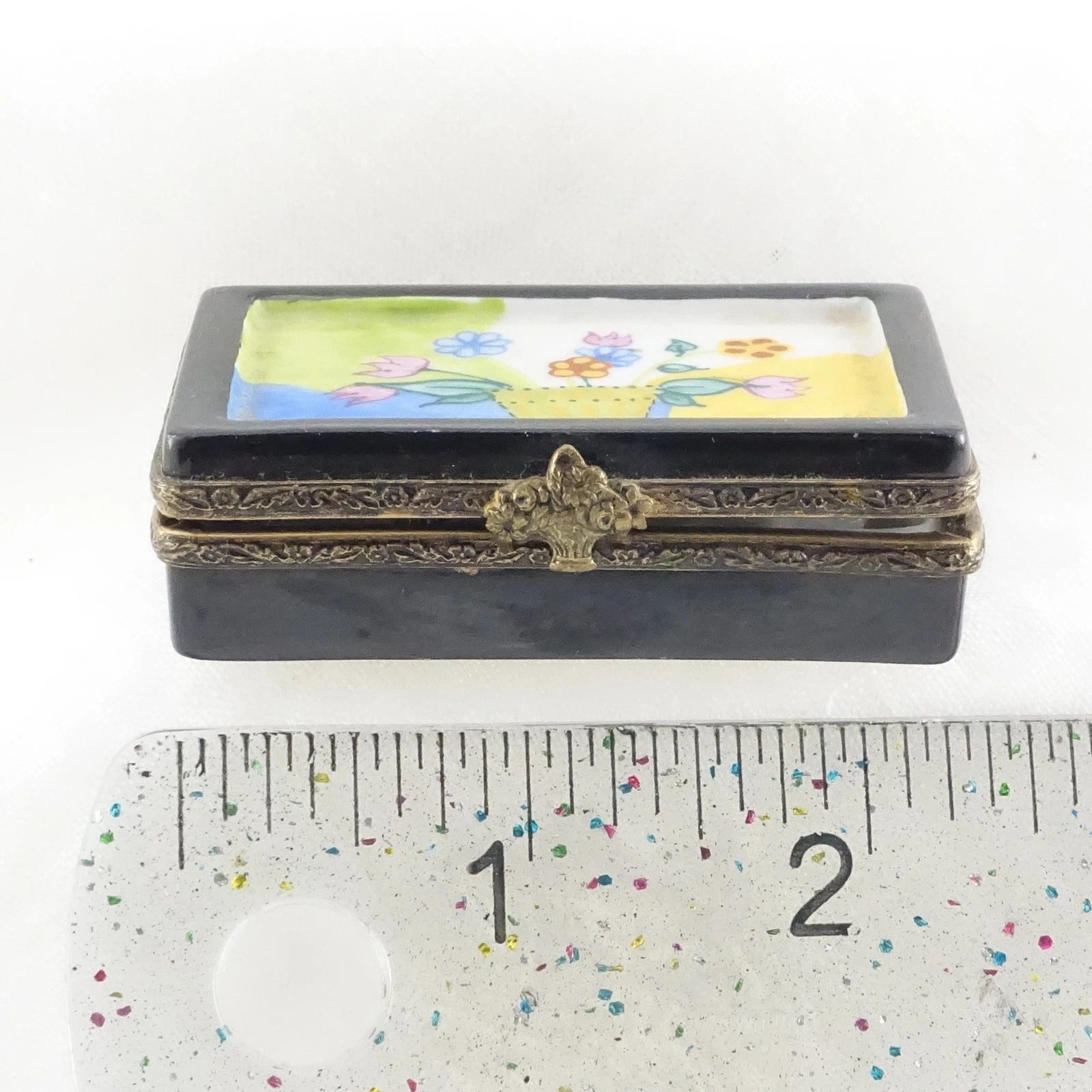 Decorative box with floral design on a white background, next to a ruler for scale.