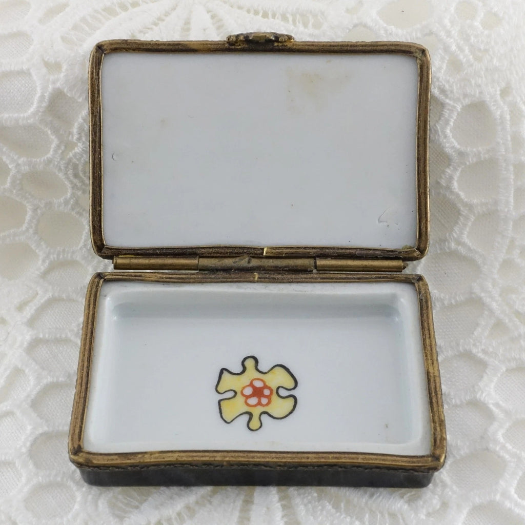 Open jewelry box with a yellow and red heart design on a textured white background