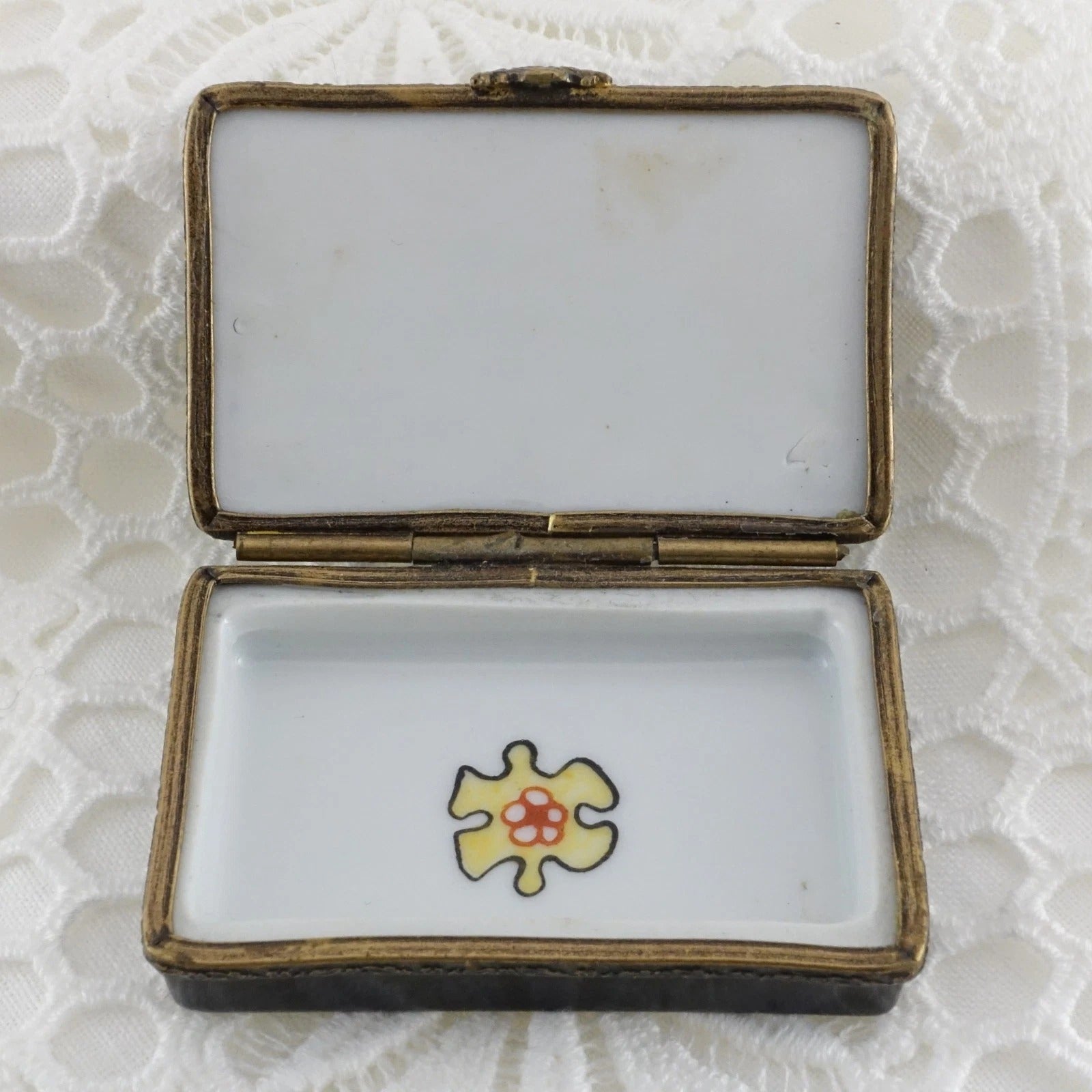 Open jewelry box with a yellow and red heart design on a textured white background