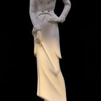 White marble statue of a figure with a draped garment on a black background