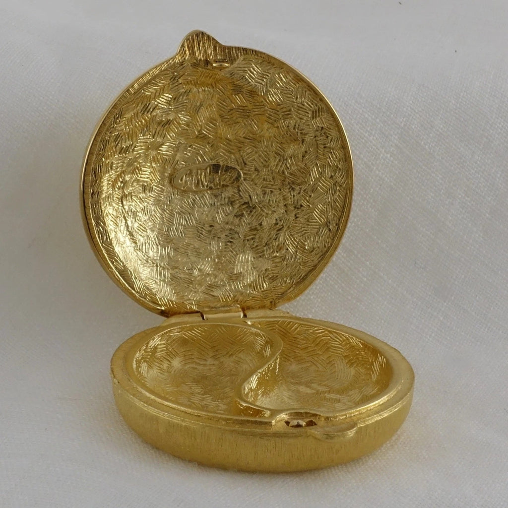 Gold locket with intricate design on a white background