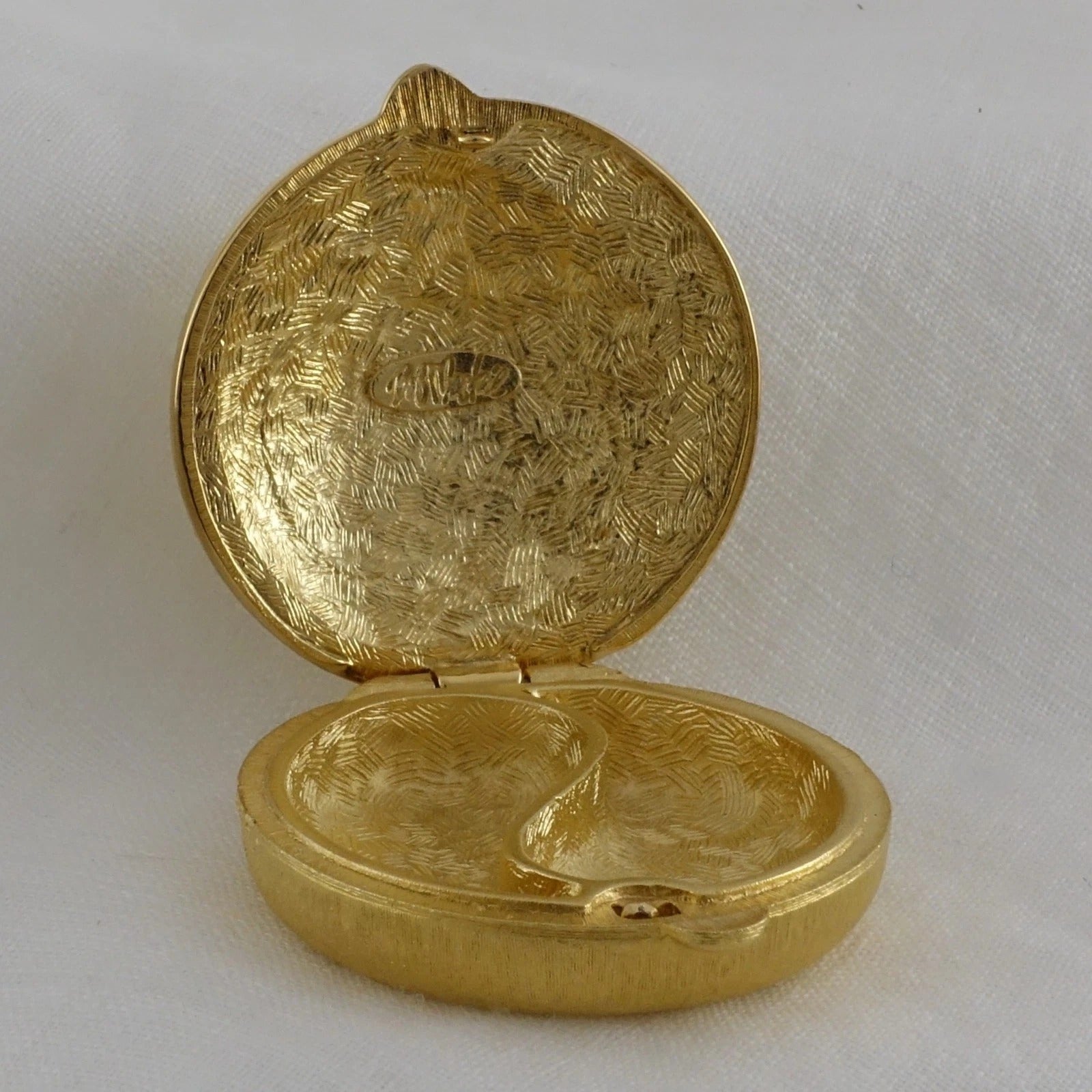 Gold locket with intricate design on a white background