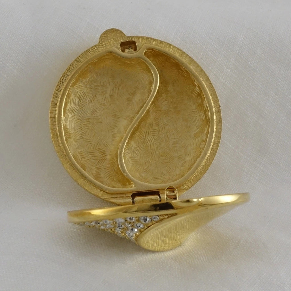 Gold compact mirror with decorative design on a white background