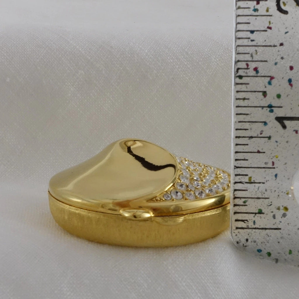 Gold heart-shaped box with decorative elements next to a ruler on a white background