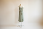 Sage green dress on a mannequin against a white background